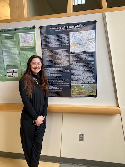 Student standing with research poster